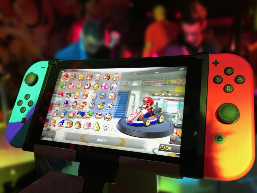 pexels-photo-371924-371924 Close-up of a Nintendo Switch showing Mario Kart selection screen, gaming atmosphere in the background.